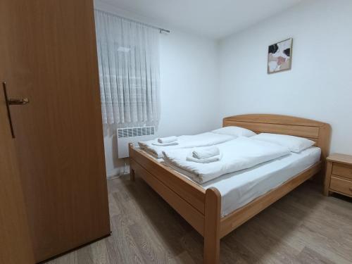 a bedroom with a bed with white sheets and a window at Divan Vlašić in Šišava