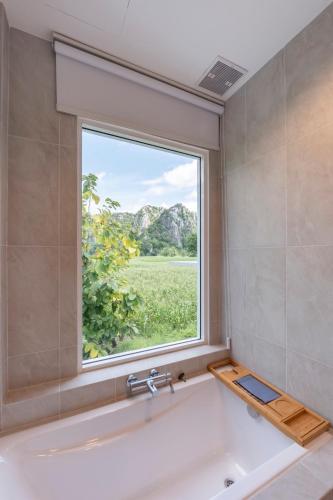 a bath tub in a bathroom with a window at Private Courtyard Villa in Sara Buri
