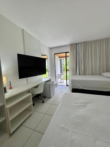 une chambre avec un lit et un bureau avec une télévision dans l'établissement Iloa Residence, à Barra de São Miguel
