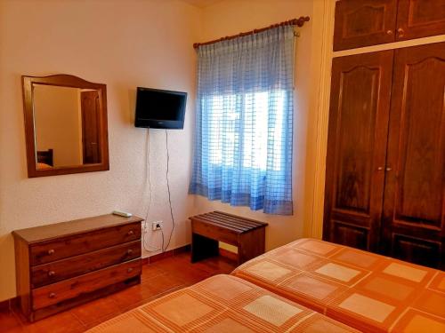 een slaapkamer met een bed, een ladekast en een spiegel bij Casa La Canela in Playa de Santiago