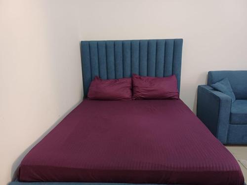 ein Bett mit einer lila Decke und einem blauen Stuhl in der Unterkunft Fully Furnished Modern Studio in a Prime Location beside Abu Dhabi Central Bus Station and Al Wahda Mall العربية استوديو حديث ومفروش بالكامل في موقع مميز بجوار محطة الحافلات المركزية ومول الوحدة في أبوظبي in Abu Dhabi