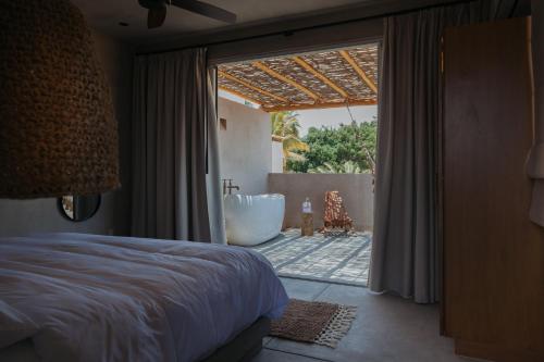 a bedroom with a bed and a bathroom with a tub at Proyecto Palmita in El Pescadero