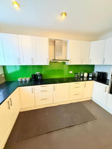 a kitchen with white cabinets and green walls at 200m to Wembley Stadium Guest Rooms in London