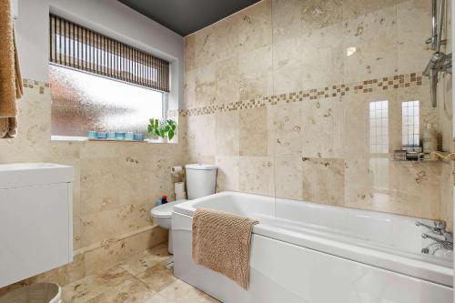 a bathroom with a tub and a toilet at Cosy 3 Bed with Parking in Bilton