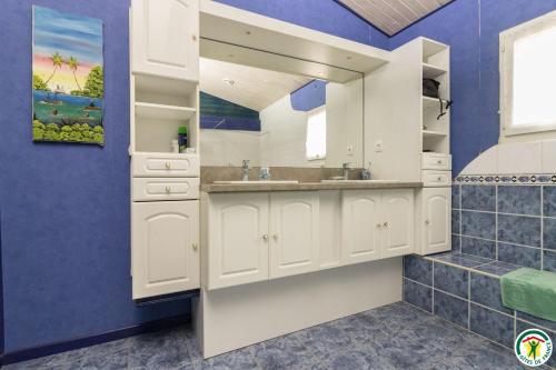 a bathroom with white cabinets and a blue wall at En savanac in Albiac