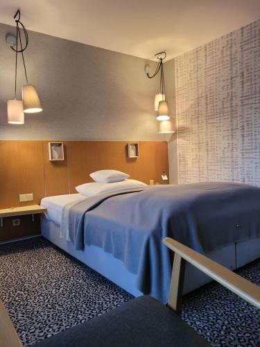 Un dormitorio con una cama grande con sábanas azules. en Hotel Scholz, en Aalen
