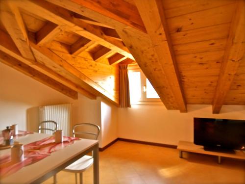 sala de estar con techo de madera, mesa y TV en Locanda Posta, en Argegno