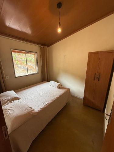 ein kleines Schlafzimmer mit einem Bett und einem Fenster in der Unterkunft Recanto Zechini in Vargem Alta