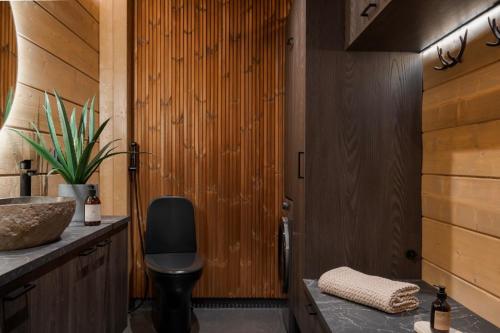 une salle de bains avec une chaise noire et un mur en bois dans l'établissement Saana's chalets Levi, à Levi