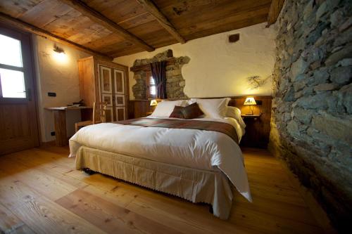 een slaapkamer met een groot bed en een stenen muur bij A barma drola in Brusson