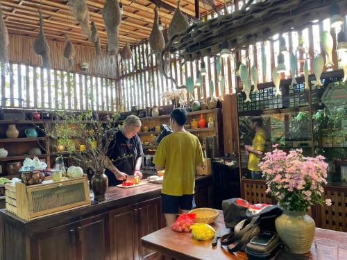 zwei Männer stehen in einer Küche und bereiten Essen vor in der Unterkunft TROPICAL GARDEN Homestay in Buôn Alê (1)