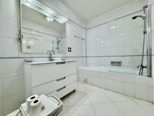 une salle de bain avec un lavabo, une baignoire et un miroir dans l'établissement Vilamoura Marina Beach With Pool by Homing, à Vilamoura