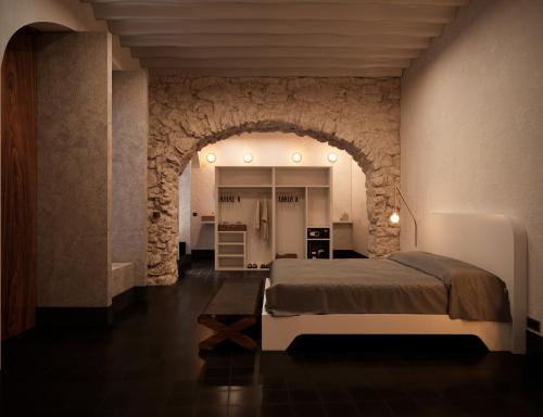 a bedroom with a large bed in a stone wall at Hotel Sevilla, a Member of Design Hotels in Mérida