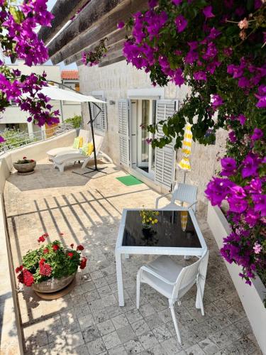 a patio with a table and chairs and flowers at JASMINE DELUXE APARTMENT with super-king bed, large sun terrace and spectacular views in Vis