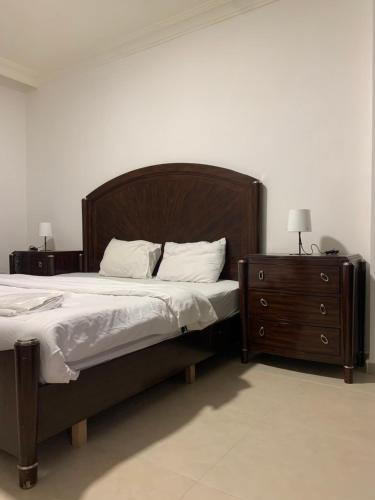 Bett mit einem Kopfteil aus Holz und einem Nachttisch in der Unterkunft dabouq 3bedroom near all services JRE in Amman