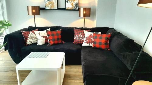 un canapé noir avec des coussins dessus dans un salon dans l'établissement Stilvolles Design-Maisonette in Schiffweiler - 2 Etagen - Self-Check-in - 2 Parkplätze - WLAN - Balkon & Garten - ruhig gelegen - Nähe See & Wald - bis 7 Pers, à Schiffweiler