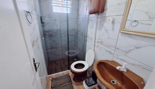 ein Badezimmer mit Dusche, Toilette und Waschbecken in der Unterkunft KITNET S4 em TORRES-RS - Confortável com cama casal box, cama de solteiro bicama, televisão, geladeira, micro-ondas, chaleira elétrica, ar-condicionado split - Anfitriã Superhost no BnB in Torres