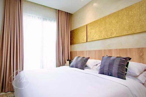 Un dormitorio con una gran cama blanca con dos almohadas. en Stylish Spacious Studio with Pool & Fitness Centre, en Accra