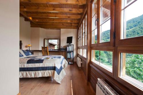 a bedroom with large windows and a bed in it at La Casona de Riomera in Santibáñez de la Fuente