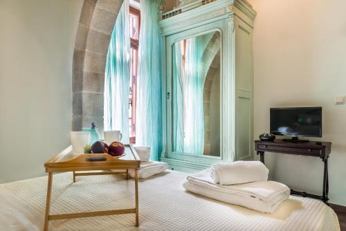 ハニア・タウンにあるPlaza Apartmentのベッド1台、テーブル、鏡が備わる客室です。