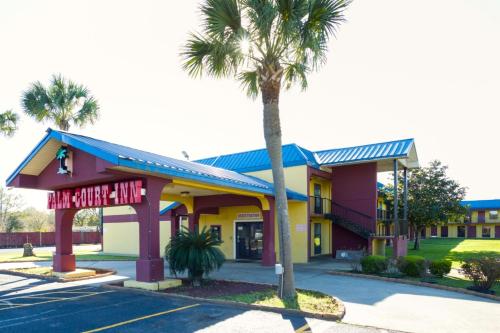 a hotel with a palm tree in a parking lot at OYO Hotel Pensacola I-10 & Hwy 29 in Pensacola