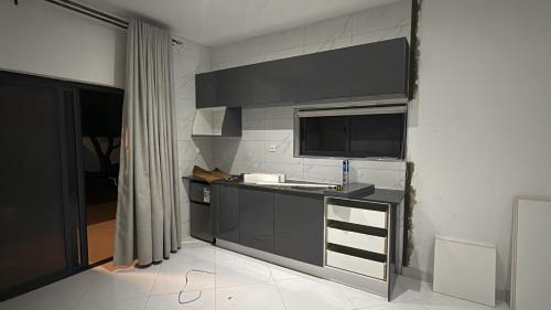 cocina con armarios negros y TV en la pared en Built2Last Beach Houses, en Xai-Xai