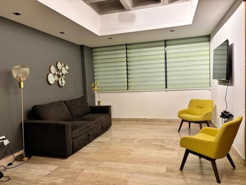 a living room with a brown couch and yellow chairs at Departamento completo con balcon en Av Carranza in San Luis Potosí