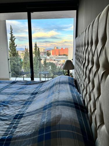a bedroom with a bed and a large window at Departamento completo con balcon en Av Carranza in San Luis Potosí
