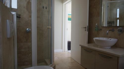 a bathroom with a sink and a glass shower at Seaside apartment - Big Bay beach in Cape Town