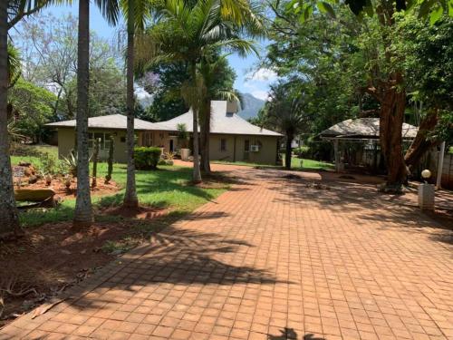 una pasarela de ladrillo frente a una casa con palmeras en Hazel Nest Ezulwini, en Ezulwini