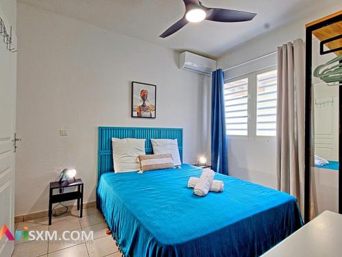 a bedroom with a blue bed with a blue blanket at Appartement cosy à Grand Case, proche plage, piscine, parking et Wi-Fi inclus - FR-1-734-77 in Marigot