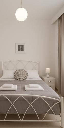 a white bedroom with a large bed with two towels at Athanasia's Place in Ermoupoli