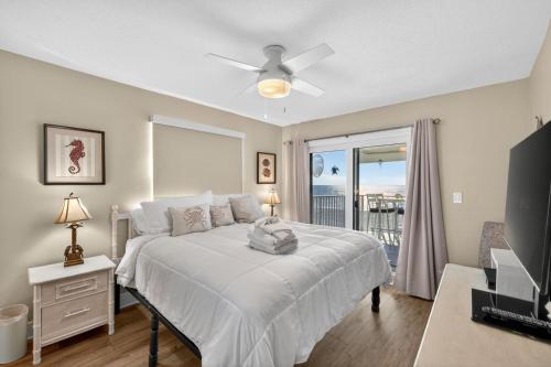 a bedroom with a white bed and a balcony at Holiday Villas II Unit 301 in Clearwater Beach