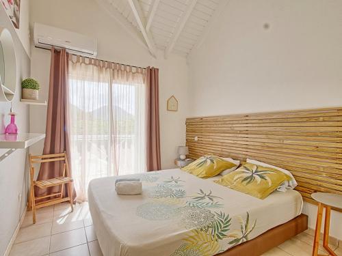 une chambre avec un grand lit avec une tête de lit en bois dans l'établissement Cocotier Charme, Confort & Détente près dOrient Bay - FR-1-734-78, à Cul de Sac
