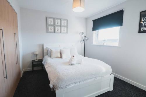 a bedroom with a white bed with a teddy bear on it at Top-Floor 2-Bed Near Braehead in Renfrew