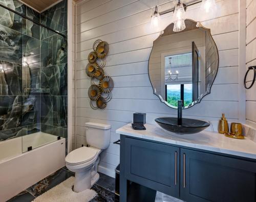 een badkamer met een wastafel, een toilet en een spiegel bij Great Smoky Getaway in Greystone Heights