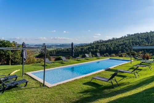 a pool with chairs and umbrellas on the grass at Casas de Fralães in Grimancelos
