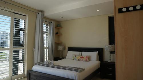 a bedroom with a bed and a large window at Seaside apartment - Big Bay beach in Cape Town