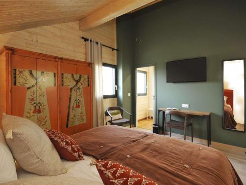 une chambre avec un lit et une télévision au mur dans l'établissement Maison de campagne éco-construite, spa, proche Nancy, tout confort, petit-déjeuner inclus - FR-1-584-83, à Voinémont