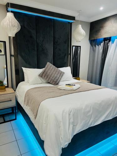 a bedroom with a large white bed with blue lighting at The Wired Nest in Ellisras