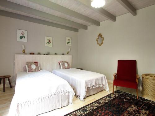 une chambre avec deux lits et une chaise rouge dans l'établissement Ferme du XIXe avec cheminée, près des gorges du Doulon - FR-1-582-227, à Frugières-le-Pin