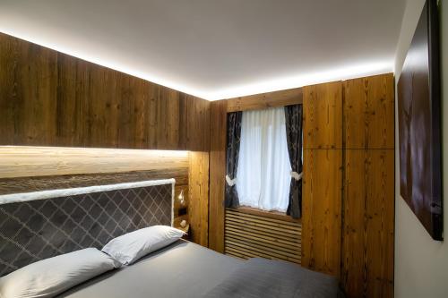 a bedroom with a bed and a window at Apt Design a Campiglio 400m funivie in Madonna di Campiglio