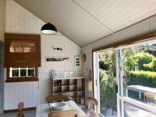 een keuken met een tafel en stoelen en een raam bij Bay of Islands - Vineyard Cottage, chic private stunning view in Purerua