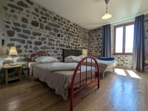 une chambre avec deux lits et un mur en pierre dans l'établissement Maison de caractère avec grand terrain, proche d'Arlempdes, labels ECOGÎTE et Tourisme & Handicap - FR-1-582-118, à Arlempdes