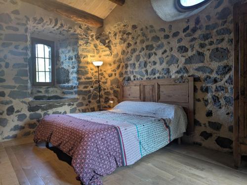 a bedroom with a bed in a room with stone walls at Élégante maison de maître XVIIIe, jardin clos 500m², nature, proche Puy-en-Velay, 11 pers., cosy & confort - FR-1-582-315 in Arsac-en-Velay