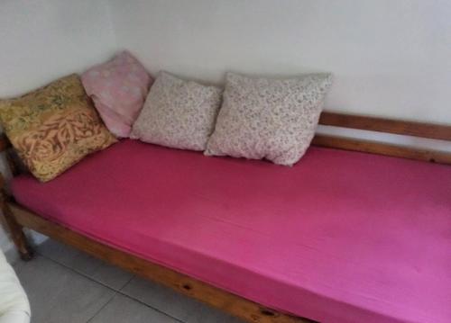 ein rosa Sofa mit Kissen darauf in der Unterkunft Chambre indépendante calme pour femmes, en forêt, 1km plage in Deshaies
