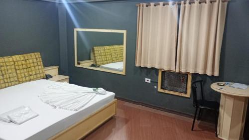 een slaapkamer met een bed, een spiegel en een tafel bij Hotel Porto Calem in Sao Paulo