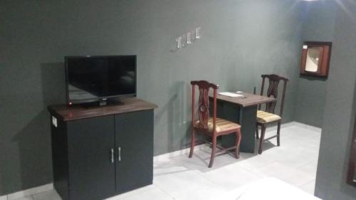 een woonkamer met een tv en een tafel met stoelen bij Hotel Porto Calem in Sao Paulo