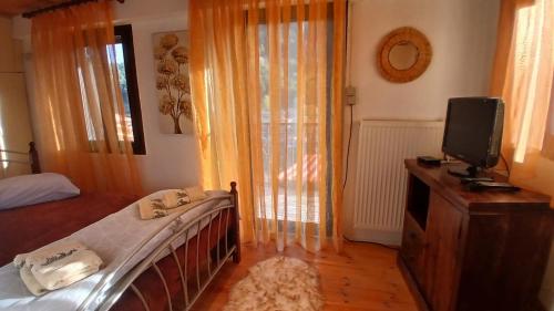 a bedroom with a bed and a tv and curtains at family home in Dhimitsana