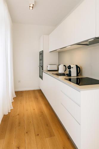 a kitchen with white cabinets and a wooden floor at Adorable Apartment City Center with Parking, Near Tram in Luxembourg